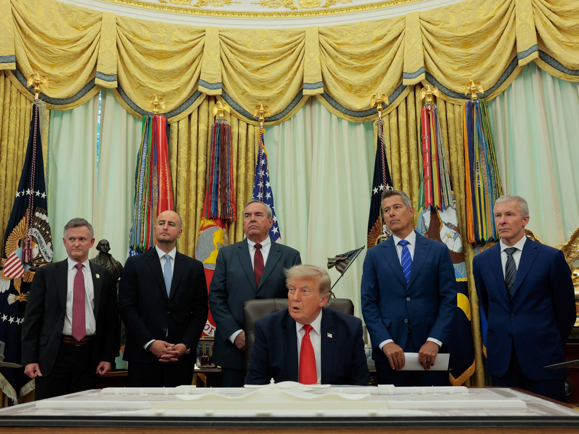 U.S. President Donald Trump sits behind an airport model, next to the CEO of United Airlines, Scott Kirby, and U.S. Secretary of Transportation Sean Duffy, during an announcement about a $22.5 billion renovation of Washington Dulles International Airport in the Oval Office at the White House in Washington, D.C., U.S., July 29, 2026. REUTERS/Kylie Cooper
